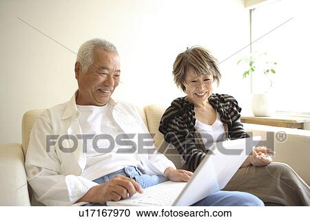 Senior man and mature woman looking at laptop monitor on sofa, smiling View Large Photo Image Stock Image - Senior man and mature woman looking at laptop monitor on sofa, smiling. Fotosearch