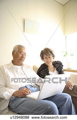 Senior man and mature woman looking at laptop monitor on sofa, smiling View Large Photo Image Stock Photo - Senior man and mature woman looking at laptop monitor on sofa, smiling. Fotosearch