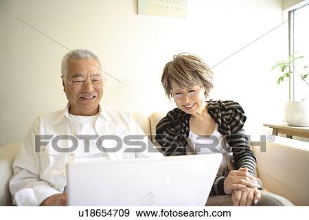Senior man and mature woman looking at laptop monitor on sofa, smiling View Large Photo Image Stock Photo - Senior man and mature woman looking at laptop monitor on sofa, smiling. Fotosearch