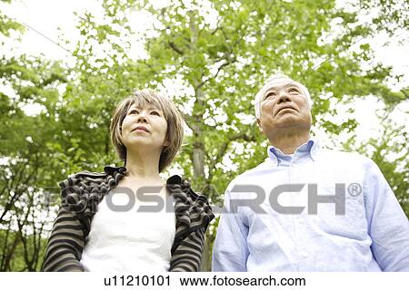 Stock Image - Senior man and mature woman standing under trees. Fotosearch