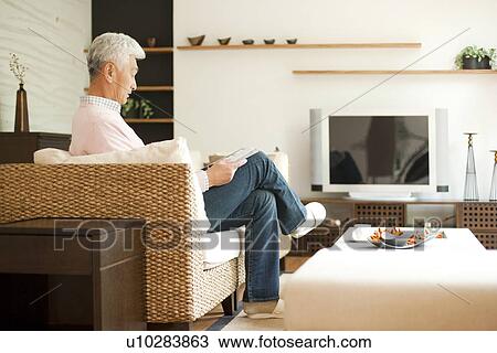 Senior man reading a book on a couch View Large Photo Image Stock Image - Senior man reading a book on a couch. Fotosearch