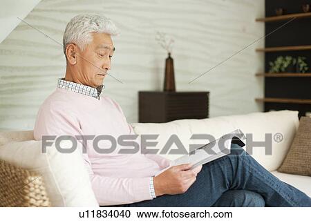 Senior man reading a book on a couch View Large Photo Image Stock Image - Senior man reading a book on a couch. Fotosearch