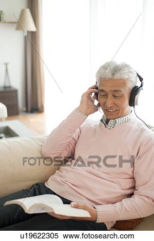 Senior man with headphones and reading a book View Large Photo Image Stock Photography - Senior man with headphones and reading a book. Fotosearch