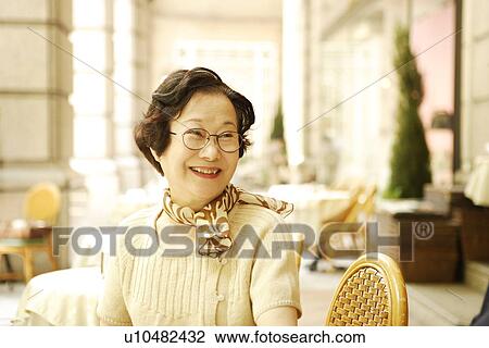 Senior woman sitting at table in cafe, smiling View Large Photo Image Stock Image - Senior woman sitting at table in cafe, smiling. Fotosearch