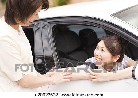 Stock Image - Senior woman talking to her daughter in car, smiling. Fotosearch