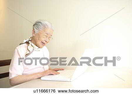 Stock Photograph - Senior woman using laptop, smiling, white background. Fotosearch
