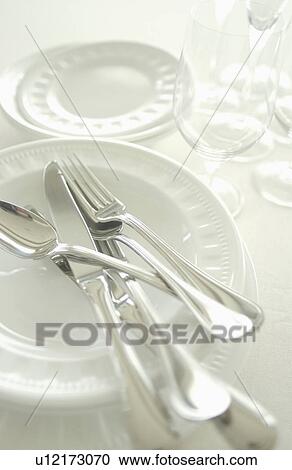 Stock Image - Still life of plates, wineglasses and silverware. Fotosearch