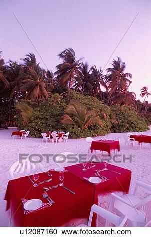 Stock Image - Table and place setting on the beach, Maldives. Fotosearch
