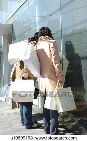 Three young women window shopping View Large Photo Image Stock Photo - Three young women window shopping. Fotosearch