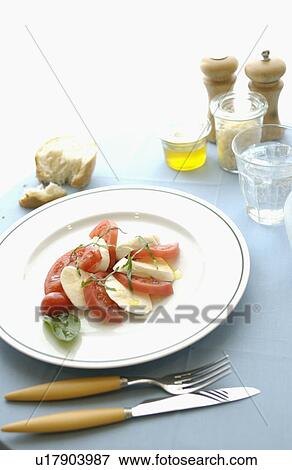 Tomatoes, mozzarella and basil salad on dining table View Large Photo Image Stock Photo - Tomatoes, mozzarella and basil salad on dining table. Fotosearch