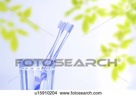 Picture - Toothbrushes in glass, white background, differential focus. Fotosearch