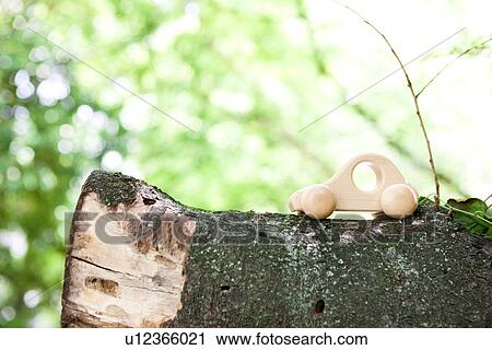 Stock Image - Toy car on tree trunk. Fotosearch