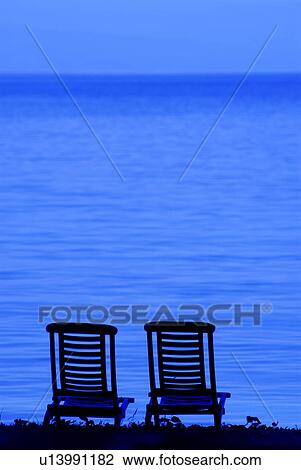 Stock Image - Two Wooden Chairs by the Sea. Fotosearch