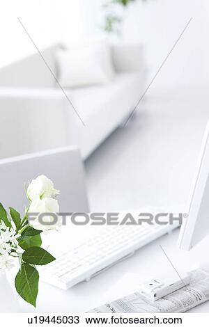 Stock Image - Vase of white roses and computer on table. Fotosearch