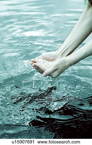 Stock Image - Woman scooping up water with hands. Fotosearch