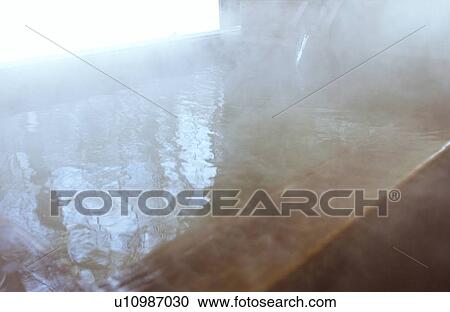 Stock Image - Wooden bathtub filled with hot spring, close up. Fotosearch