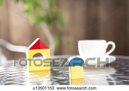 Stock Image - Wooden houses and cup of coffee on table, differential focus. Fotosearch