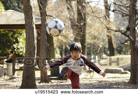 Stock Image - Young boy playing soccer, Tokyo Prefecture, Honshu, Japan. Fotosearch