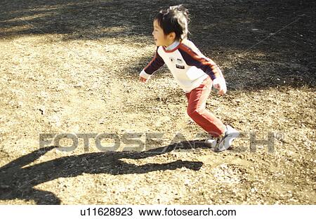 Stock Image - Young boy running, Tokyo Prefecture, Honshu, Japan. Fotosearch
