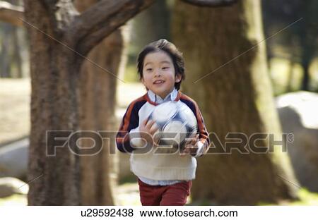 Stock Photo - Young boy running with soccer ball, Tokyo Prefecture, Honshu, Japan. Fotosearch