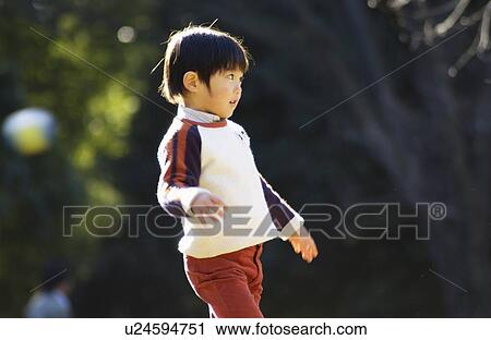 Stock Image - Young boy standing, side view, Tokyo Prefecture, Honshu, Japan. Fotosearch