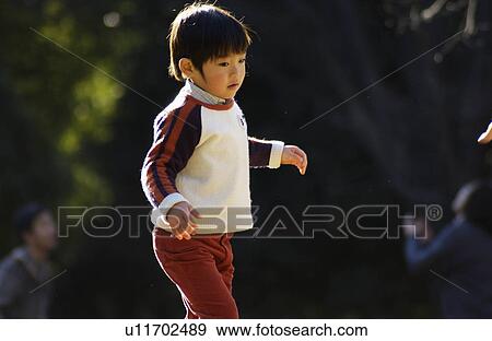 Stock Photo - Young boy standing, side view, Tokyo Prefecture, Honshu, Japan. Fotosearch