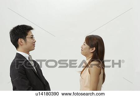 Stock Image - Young Business Man and Woman Standing Face to Face. Fotosearch