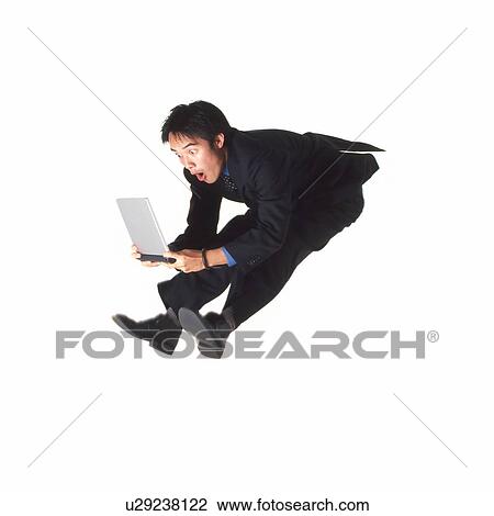 Stock Image - Young businessman jumping with laptop. Fotosearch