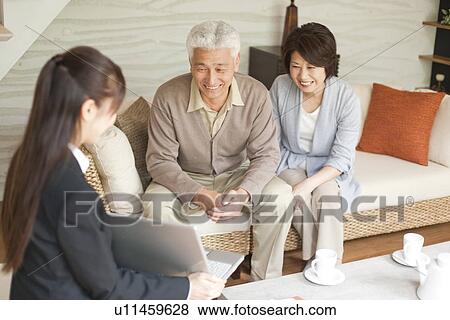 Stock Photo - Young businesswoman showing computer monitor to senior couple. Fotosearch