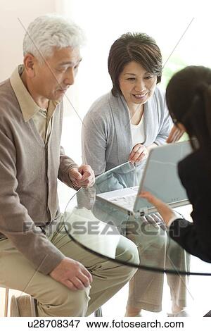 Stock Photo - Young businesswoman showing computer monitor to senior couple. Fotosearch