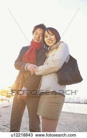 Stock Image - Young couple looking at camera, Low angle view. Fotosearch