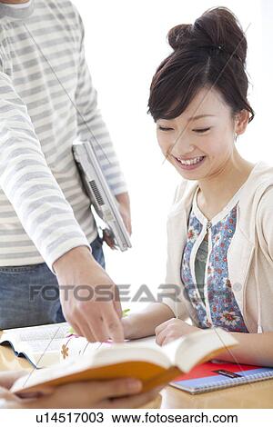 Stock Image - Young man pointing at dictionary. Fotosearch