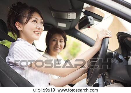 Stock Photo - Young woman and senior woman in car, smiling. Fotosearch