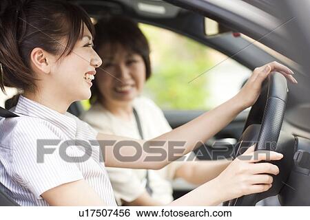 Stock Photograph - Young woman and senior woman in car, smiling. Fotosearch