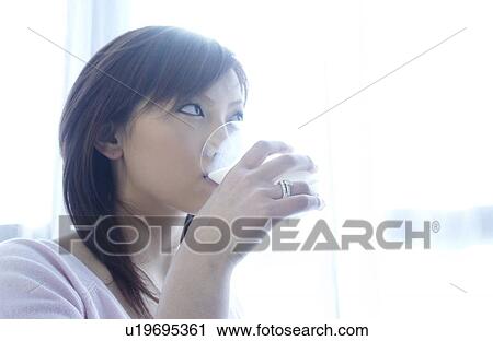 Stock Image - Young woman drinking glass of milk. Fotosearch