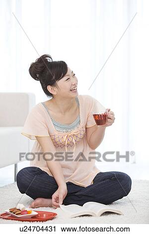 Young woman drinking tea while reading a book View Large Photo Image Stock Image - Young woman drinking tea while reading a book. Fotosearch