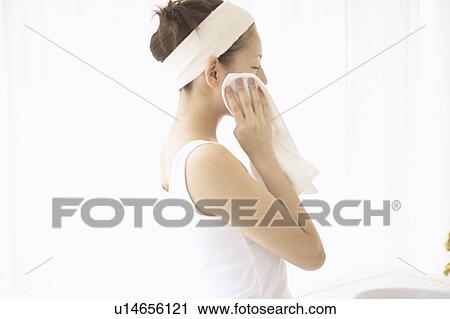 Stock Image - Young woman drying face. Fotosearch