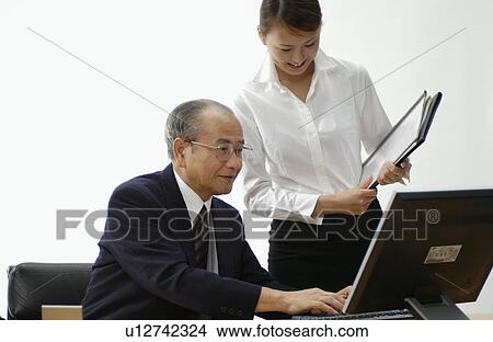 Picture - Young Woman Executive Assistant and Her Boss at Office. Fotosearch