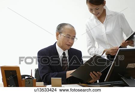 Young Woman Executive Assistant Looking at File with Her Boss View Large Photo Image Picture - Young Woman Executive Assistant Looking at File with Her Boss. Fotosearch