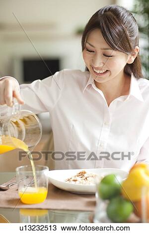 Young woman having breakfast, pouring orange juice into glass View Large Photo Image Stock Image - Young woman having breakfast, pouring orange juice into glass. Fotosearch