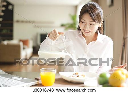 Young woman having breakfast, pouring milk into bowl of cereal View Large Photo Image Stock Image - Young woman having breakfast, pouring milk into bowl of cereal. Fotosearch