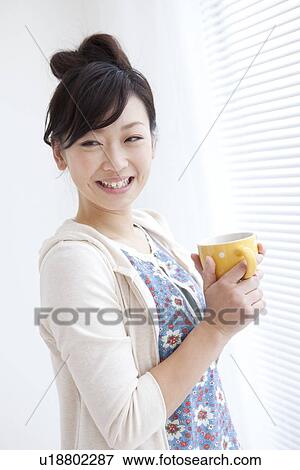 Young woman holding coffee and smiling View Large Photo Image Stock Photo - Young woman holding coffee and smiling. Fotosearch