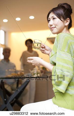 Young woman holding cup of herb tea, parents in background, differential focus View Large Photo Image Stock Image - Young woman holding cup of herb tea, parents in background, differential focus. Fotosearch