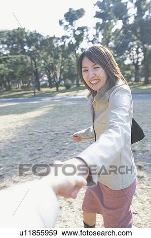 Stock Photo - Young woman holding hands of a young man. Fotosearch