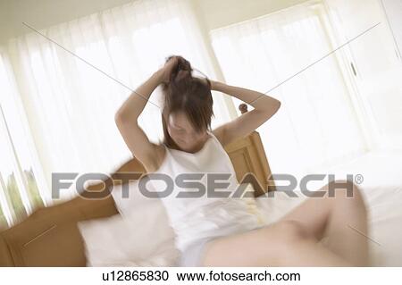 Young woman holding up hair on bed, blurred motion View Large Photo Image Stock Image - Young woman holding up hair on bed, blurred motion. Fotosearch