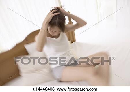 Young woman holding up hair on bed, blurred motion View Large Photo Image Stock Photo - Young woman holding up hair on bed, blurred motion. Fotosearch