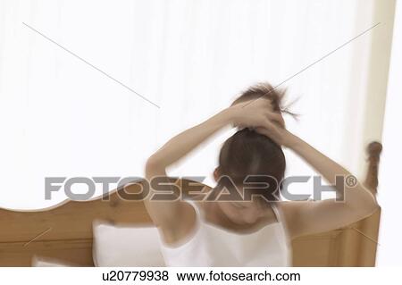 Young woman holding up hair on bed, blurred motion View Large Photo Image Stock Photo - Young woman holding up hair on bed, blurred motion. Fotosearch