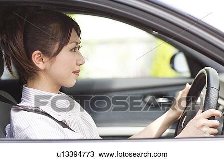 Stock Image - Young woman in car, smiling. Fotosearch