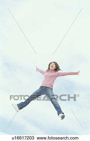Stock Image - Young woman jumping in air. Fotosearch