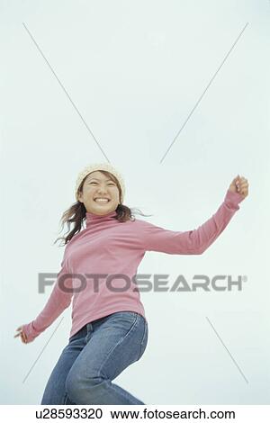 Stock Image - Young woman jumping in air. Fotosearch